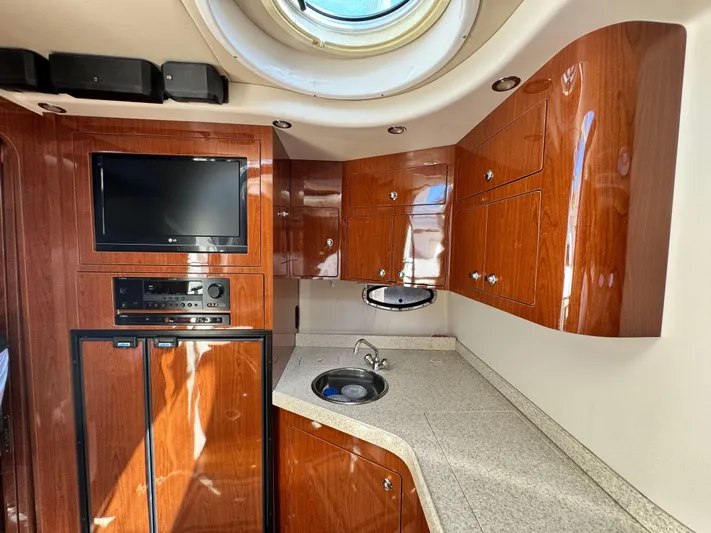 Out With The Buoys II Yacht Photos Pics 2009 Regal Commodore 4060 yacht interior with wood cabinetry, TV, and kitchenette.