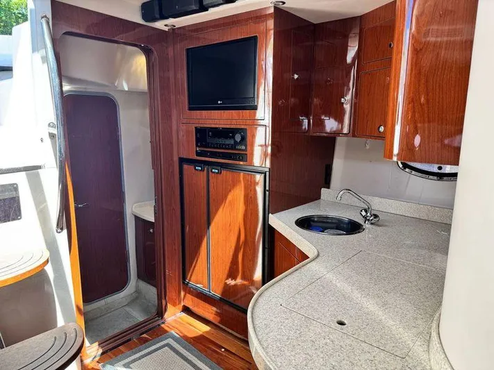 Out With The Buoys II Yacht Photos Pics Interior of 2009 Regal Commodore 4060 yacht with wood cabinetry and compact kitchen area.