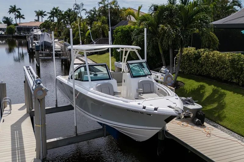  Yacht Photos Pics 2022 Pursuit DC 246 Dual Console boat docked near lush greenery and calm waters.