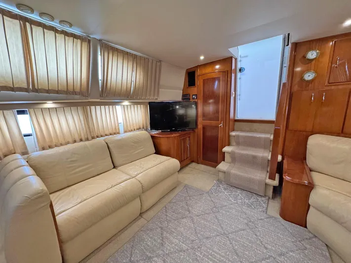 Makin Memories Yacht Photos Pics Interior of 2003 Carver 396 yacht with beige sofas, TV, and wooden cabinetry.