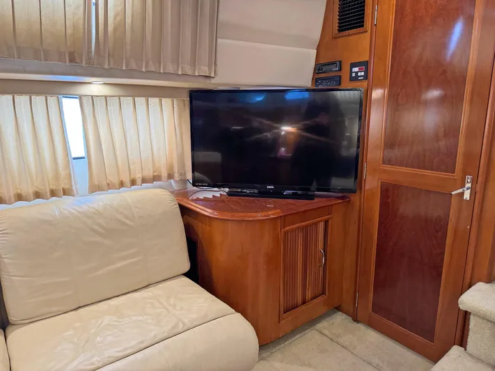 Makin Memories Yacht Photos Pics Interior of 2003 Carver 396 yacht with TV, beige sofa, and wooden cabinetry.
