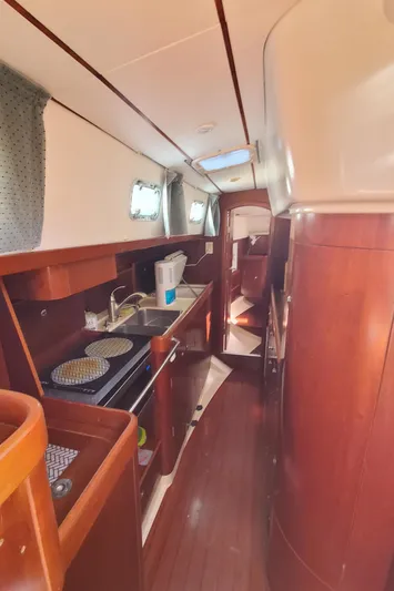  Yacht Photos Pics Interior of 1999 Beneteau Oceanis 44 CC sailboat with wooden cabinetry and compact kitchen.