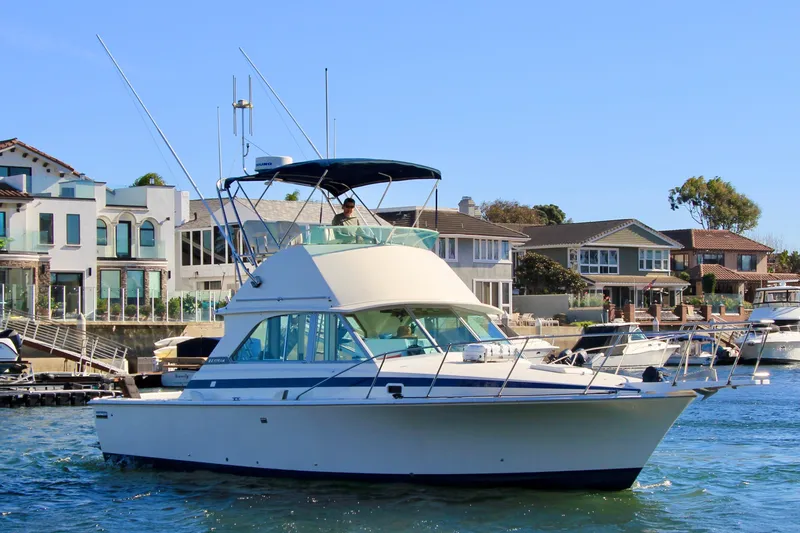 La Dorada Yacht Photos Pics 1980 Bertram 35 Flybridge yacht cruising near waterfront homes on a sunny day.