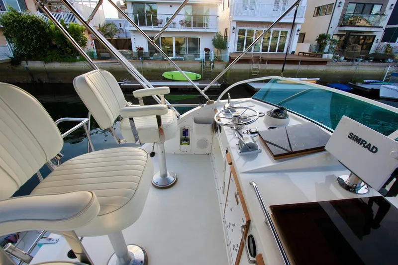 La Dorada Yacht Photos Pics 1980 Bertram 35 Flybridge helm with white seats and Simrad navigation system.