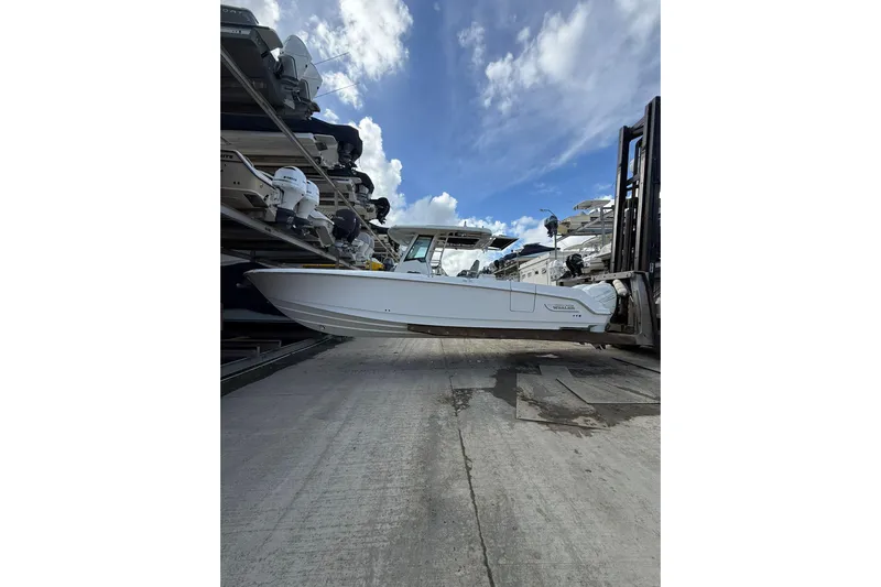  Yacht Photos Pics 2016 Boston Whaler 330 Outrage boat lifted by forklift under cloudy sky.