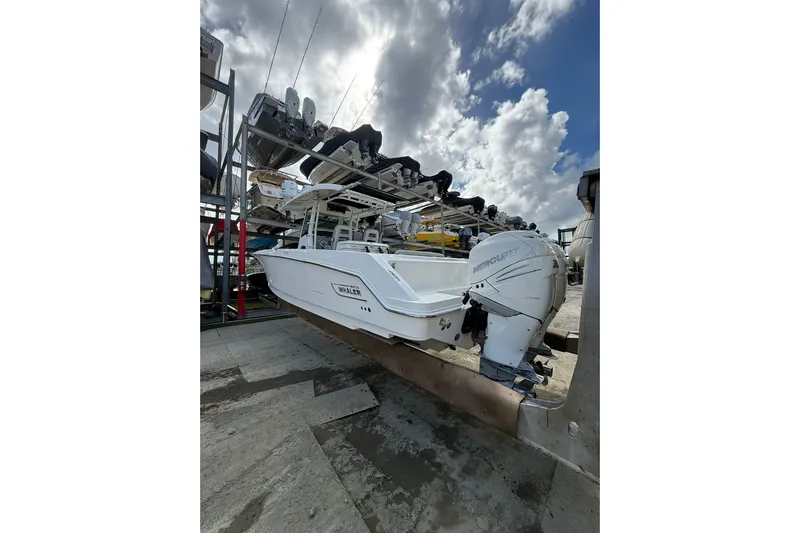  Yacht Photos Pics 2016 Boston Whaler 330 Outrage boat on a rack under a cloudy sky.