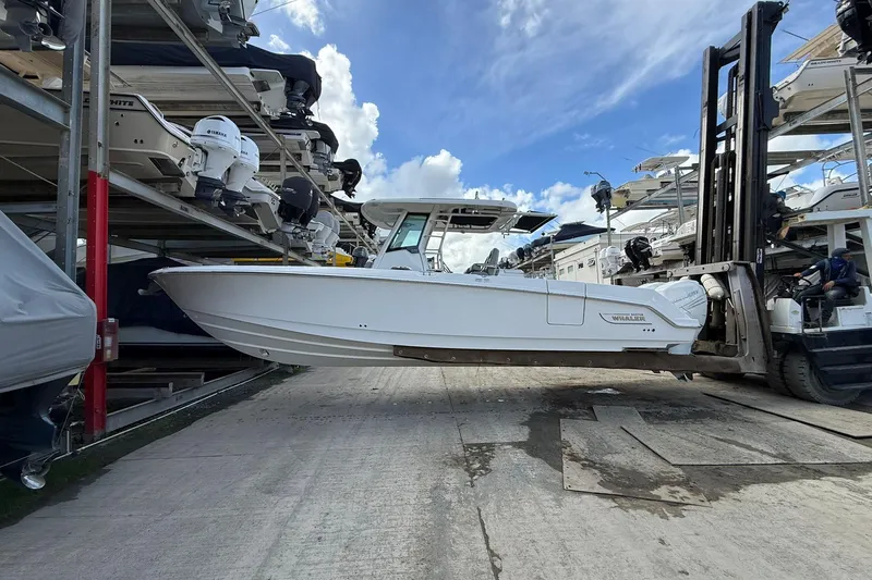  Yacht Photos Pics 2016 Boston Whaler 330 Outrage on forklift, surrounded by stacked boats under a blue sky.
