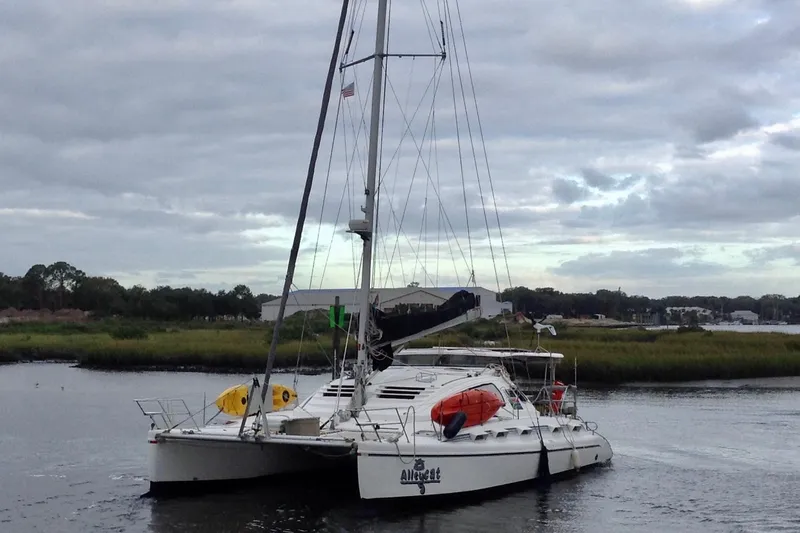 Alleycat Yacht Photos Pics 2004 Island Spirit 400 catamaran sailing on a calm river under cloudy skies.