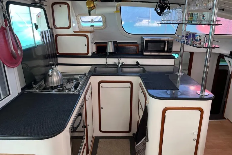 Alleycat Yacht Photos Pics Compact kitchen in a 2004 Island Spirit 400 yacht, featuring stove, sink, and microwave.