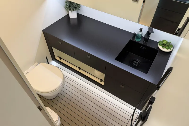  Yacht Photos Pics Modern bathroom in 2022 Vanquish VQ45 yacht with sleek black vanity and compact toilet.