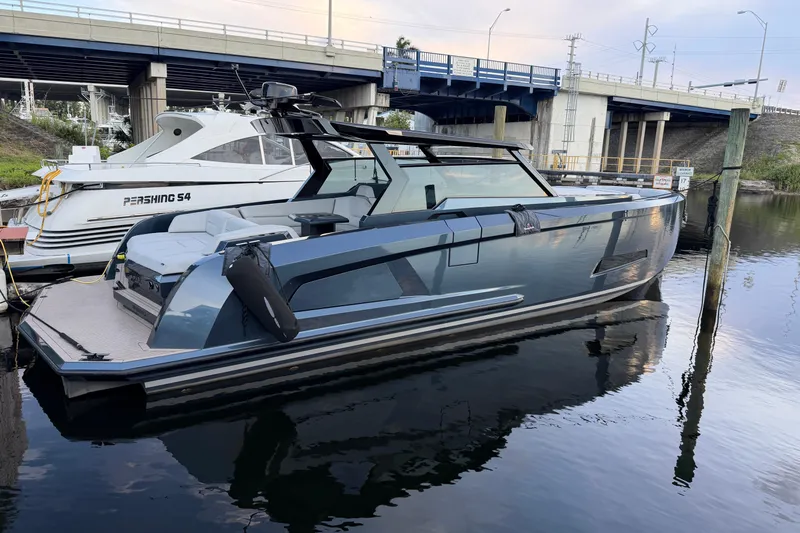  Yacht Photos Pics 2022 Vanquish VQ45 luxury yacht docked beside a Pershing S4 under a bridge.
