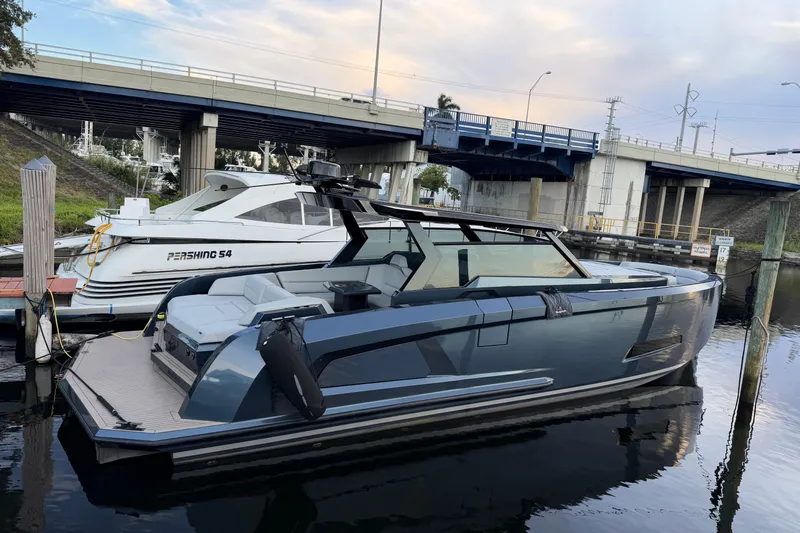  Yacht Photos Pics 2022 Vanquish VQ45 luxury yacht docked beside a Pershing S4 under a bridge.