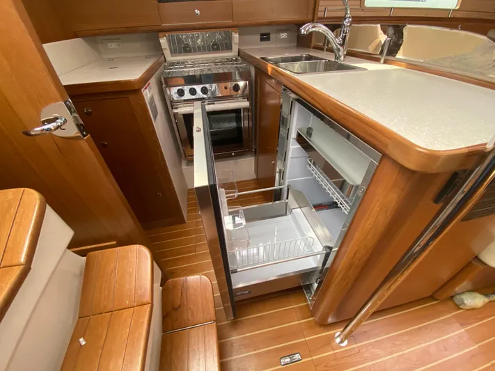 Catalina 425 In Stock Yacht Photos Pics 2024 Catalina 425 yacht interior with open fridge, stove, and wooden cabinetry.