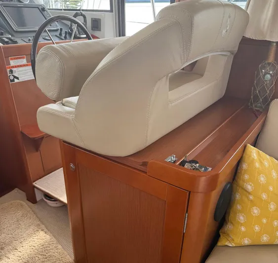 Wanderer Yacht Photos Pics 2016 Beneteau Swift Trawler 44 helm seat and dashboard, featuring beige upholstery and wooden accents.