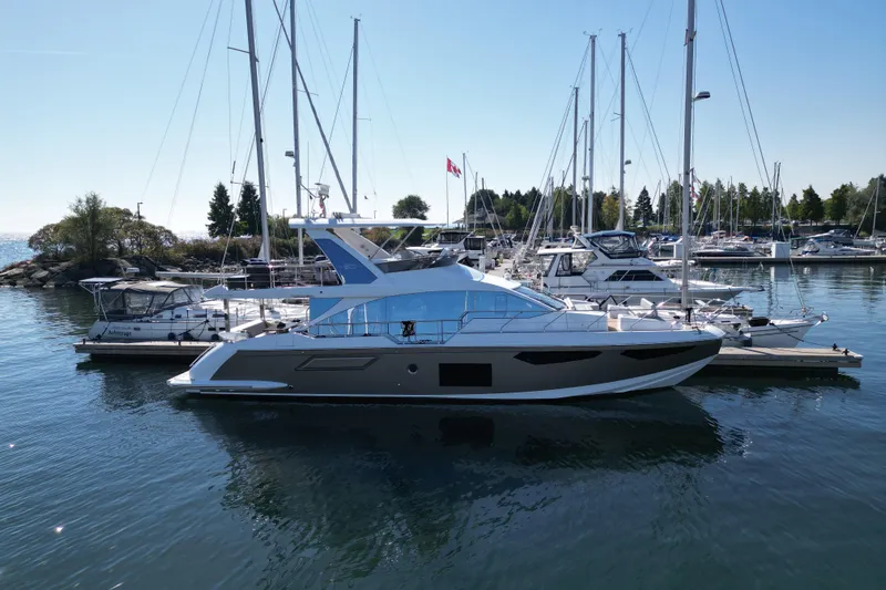  Yacht Photos Pics 2024 Azimut Fly 60 yacht docked in a marina, surrounded by sailboats.