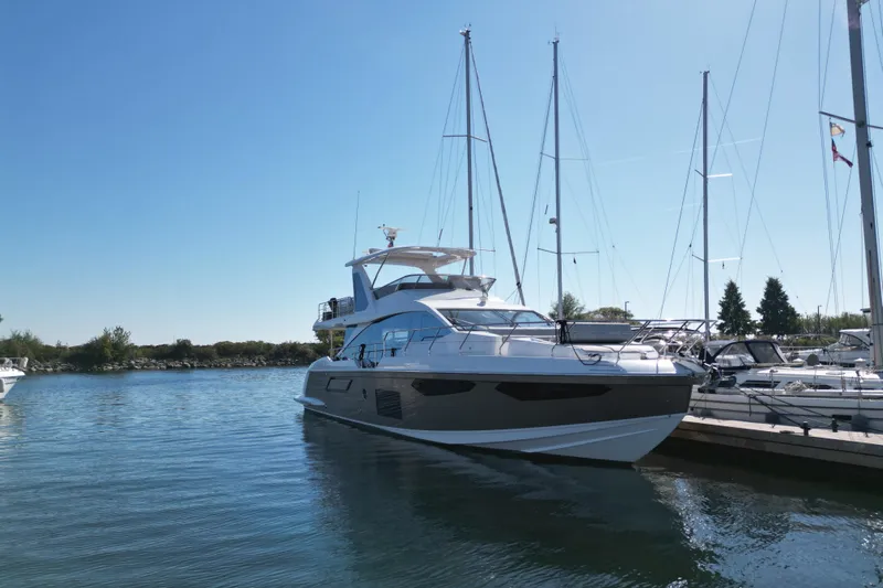  Yacht Photos Pics 2024 Azimut Fly 60 yacht docked in a serene marina under a clear blue sky.