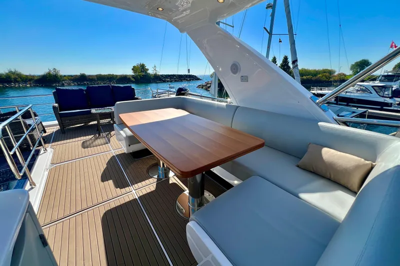 Yacht Photos Pics 2024 Azimut Fly 60 yacht deck with elegant seating and wooden table, overlooking serene waters.