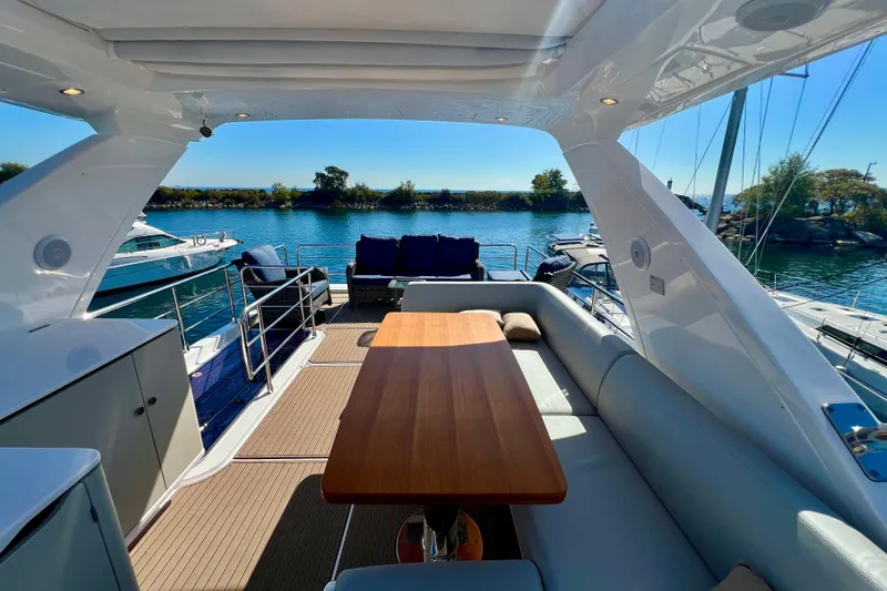  Yacht Photos Pics Luxurious 2024 Azimut Fly 60 yacht interior with elegant seating and wooden table, docked by the water.