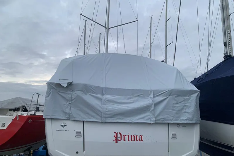 Prima Yacht Photos Pics 2024 Jeanneau Sun Odyssey 349 sailboat covered, docked alongside other boats.