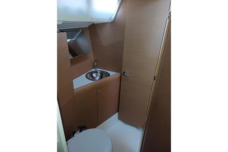 Prima Yacht Photos Pics 2024 Jeanneau Sun Odyssey 349 yacht bathroom with wooden cabinetry and stainless steel sink.