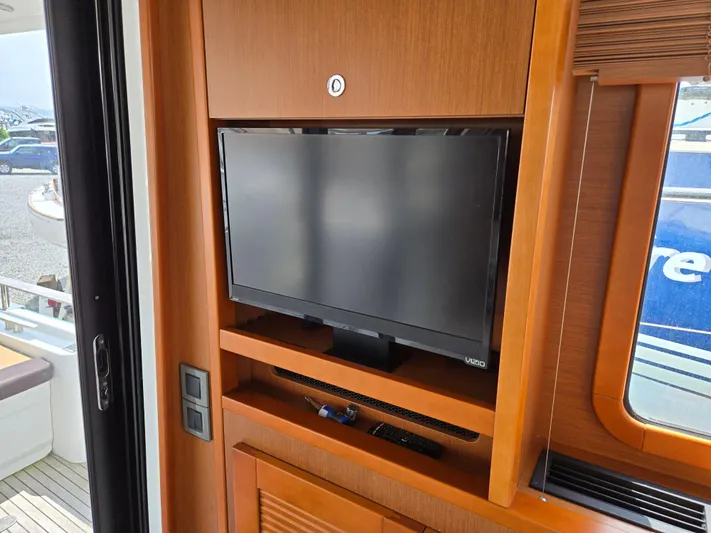 First Mates Yacht Photos Pics 2015 Beneteau Swift Trawler 44 interior with mounted TV and wooden cabinetry.