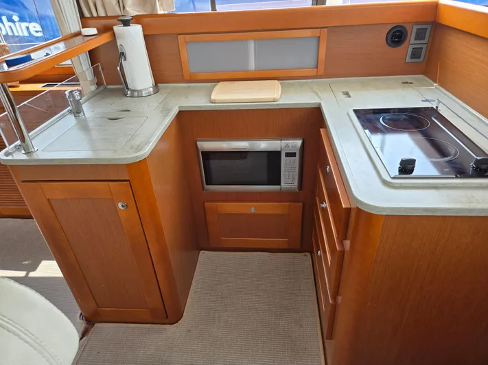 First Mates Yacht Photos Pics 2015 Beneteau Swift Trawler 44 galley with microwave, stove, and wooden cabinetry.
