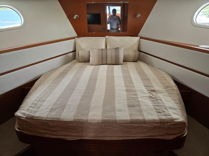 First Mates Yacht Photos Pics 2015 Beneteau Swift Trawler 44 cabin with striped bedding and porthole windows.