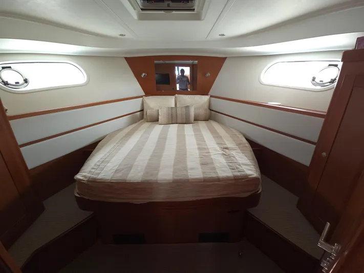 First Mates Yacht Photos Pics 2015 Beneteau Swift Trawler 44 cabin with striped bedding and wooden interior.