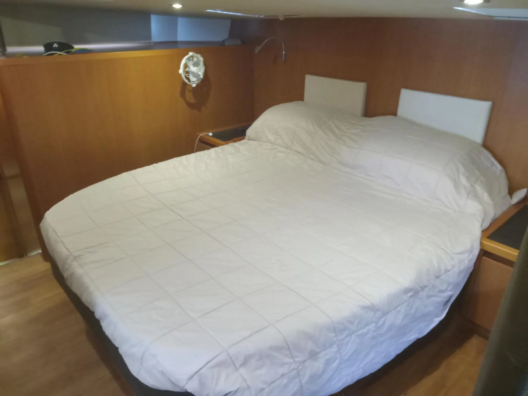 2016 Aquila 44 cabin interior with a cozy double bed and wooden paneling.