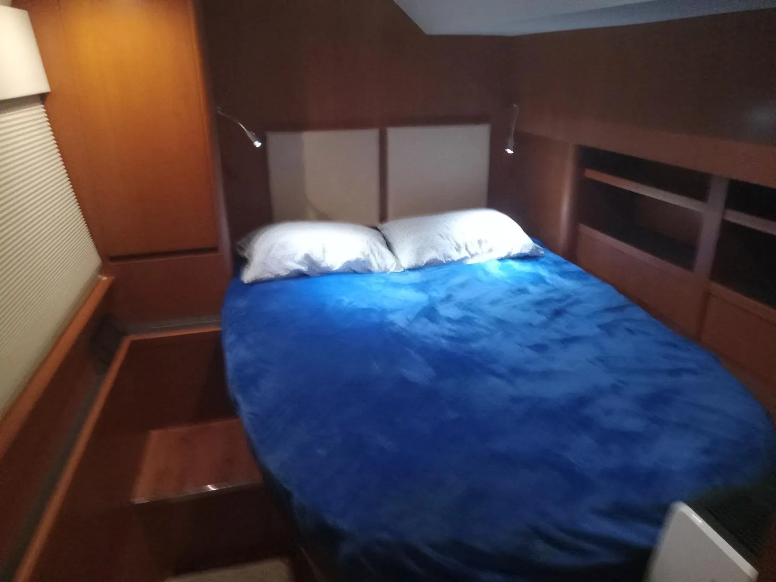 Cozy bedroom in 2016 Aquila 44 yacht with blue bedding and wooden interior.