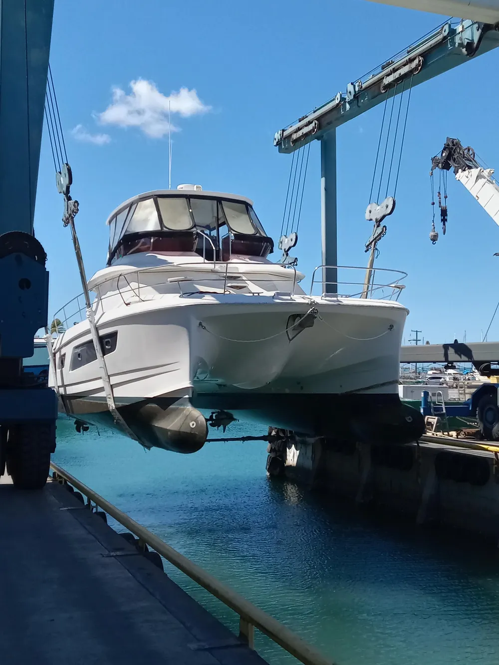 2016 Aquila 44 yacht being lifted by crane at a marina.