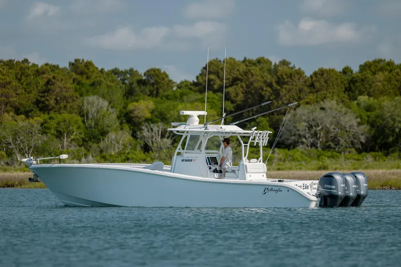  Yacht Photos Pics 2019 Yellowfin 36 boat on water with triple outboard engines, surrounded by lush greenery.