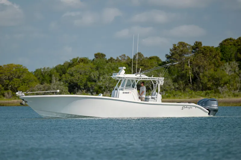 Yacht Photos Pics 2019 Yellowfin 36 boat cruising on a calm lake with lush green trees in the background.