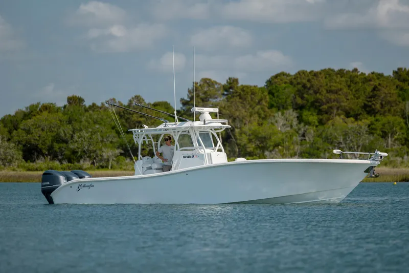  Yacht Photos Pics 2019 Yellowfin 36 boat on calm water with lush green trees in the background.