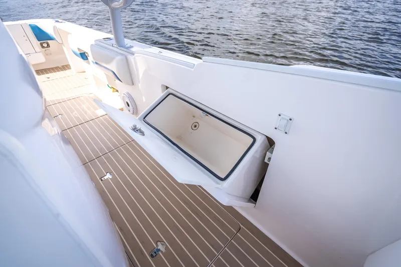  Yacht Photos Pics 2018 Intrepid 407 boat interior with open storage compartment, wooden deck, and water view.