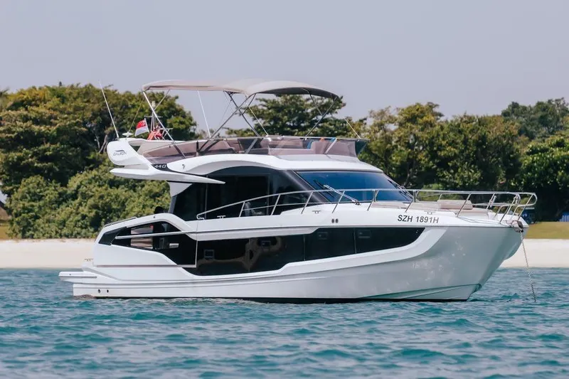  Yacht Photos Pics 2024 Galeon 440 Fly yacht on serene water, with lush greenery in the background.