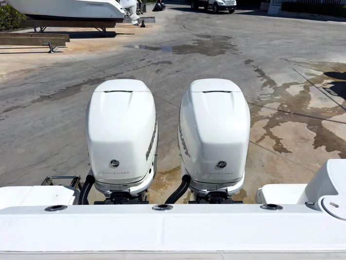 Pearl Yacht Photos Pics Twin outboard engines on a 2018 Boston Whaler 315 Conquest boat, parked on a concrete surface.