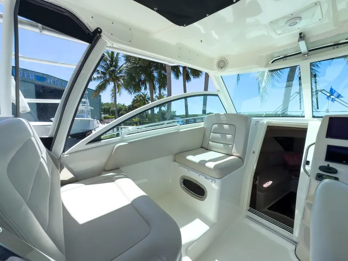 Pearl Yacht Photos Pics 2018 Boston Whaler 315 Conquest interior with seating, palm trees visible through windows.