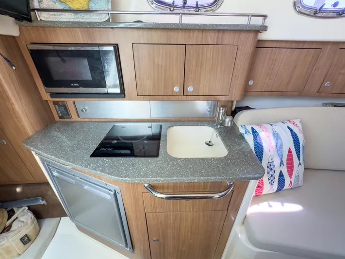 Pearl Yacht Photos Pics 2018 Boston Whaler 315 Conquest galley with microwave, stove, sink, and seating area.