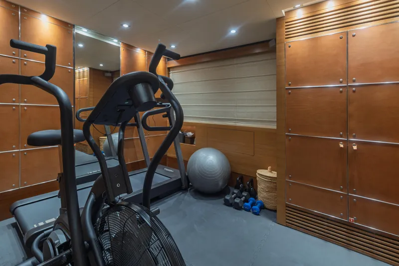 Queen Blue Yacht Photos Pics Luxury yacht gym with exercise equipment, wooden paneling, and fitness accessories on Baglietto 44 Fast, 2007.