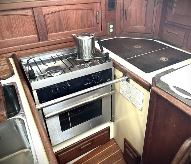 Remedy Yacht Photos Pics Galley kitchen in 1995 Pacific Seacraft 37 sailboat with stove and wooden cabinetry.
