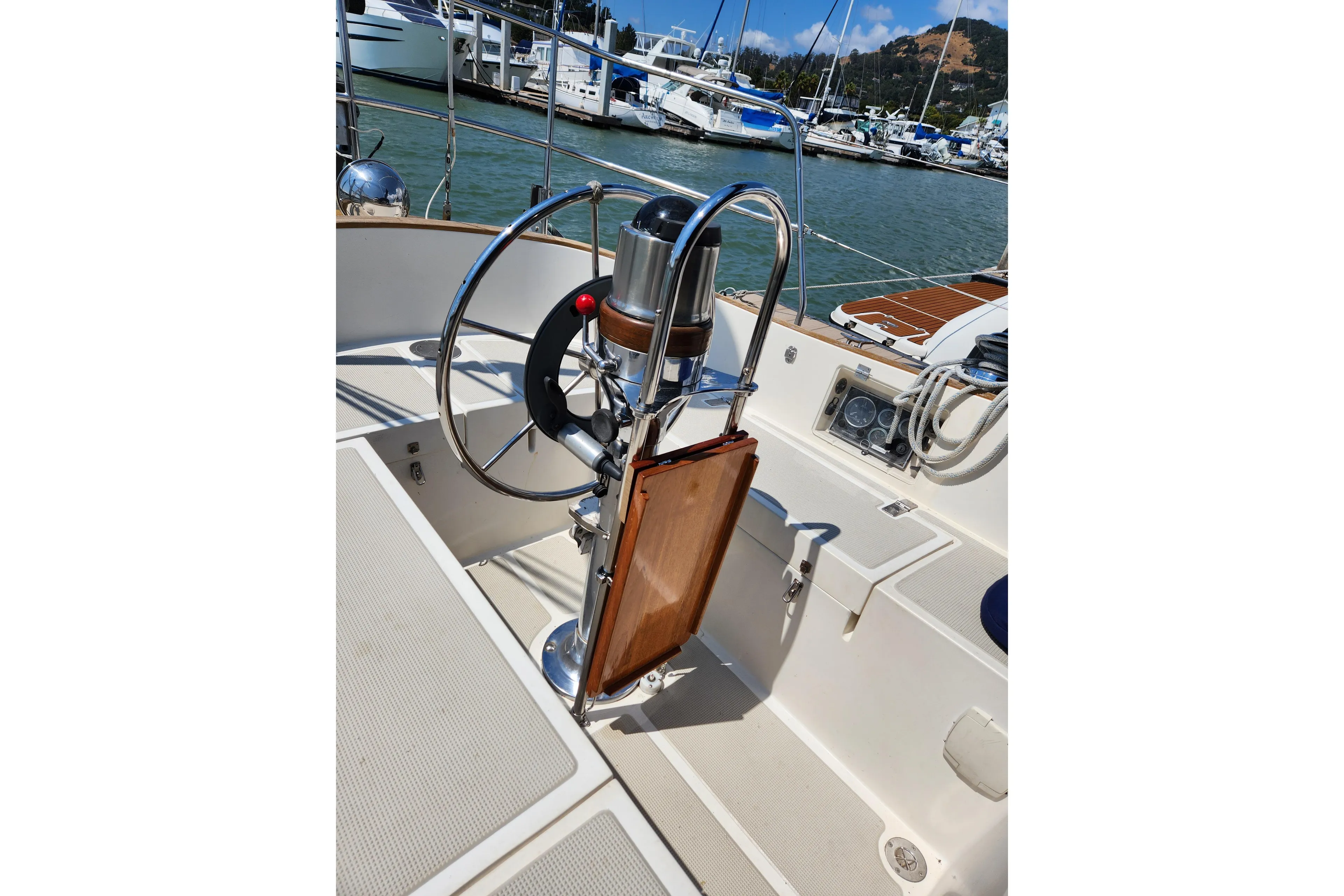 Cockpit of 1985 Mason 33 sailboat with steering wheel, docked at marina.
