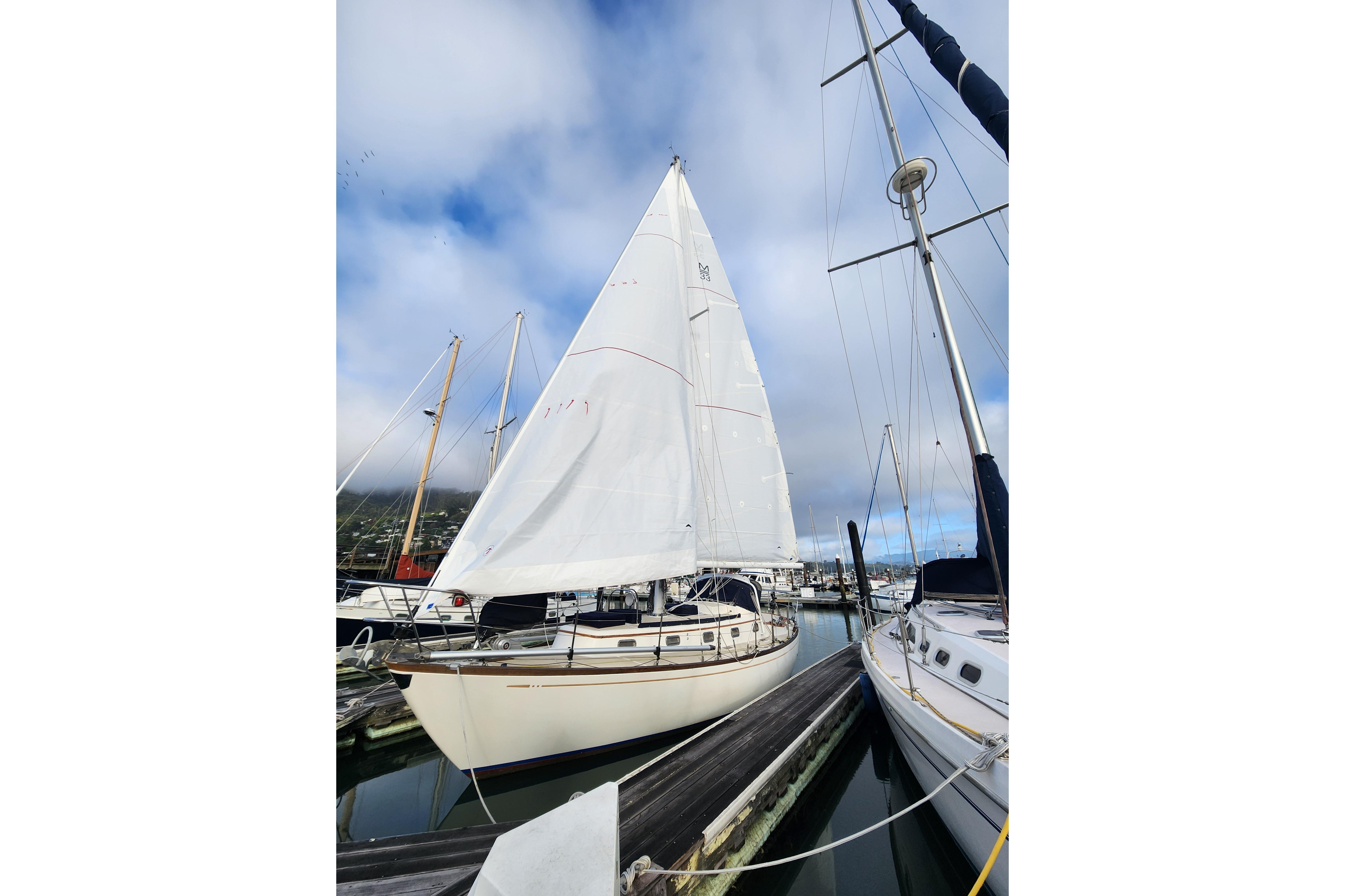 1985 Mason 33 sailboat docked at marina under cloudy sky.