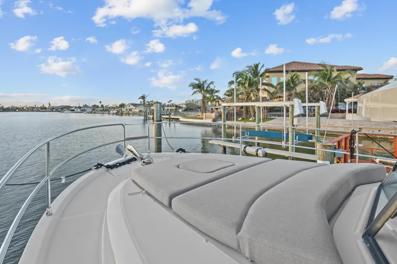 Unfiltered Yacht Photos Pics 2023 Beneteau Swift Trawler 35 docked by waterfront homes, clear sky, and palm trees.