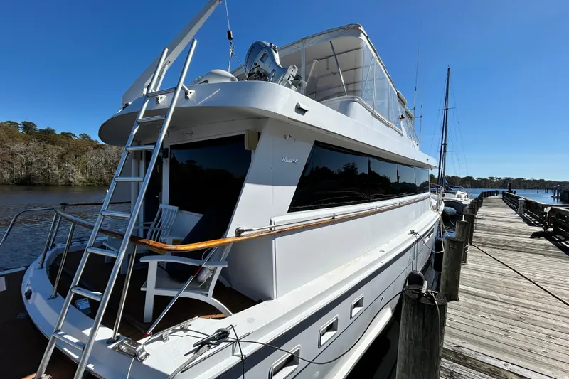 Nother Venture Yacht Photos Pics 1989 Hatteras 78 CPMY yacht docked by a wooden pier under clear blue skies.