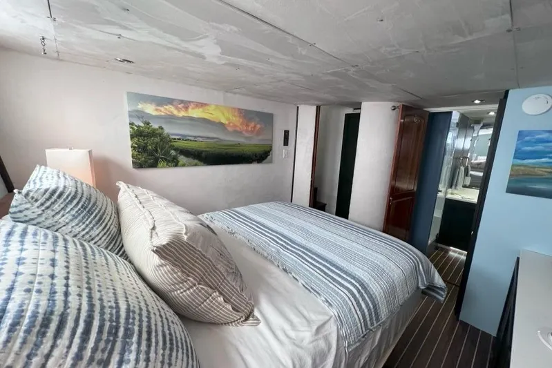 Nother Venture Yacht Photos Pics Cozy bedroom in 1989 Hatteras 78 CPMY yacht with striped bedding and scenic artwork.