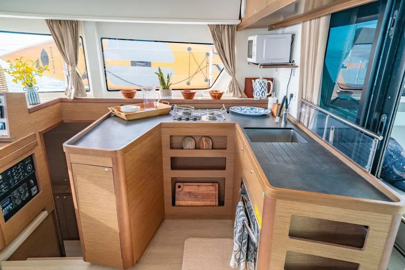 Hopena Yacht Photos Pics Interior of 2018 Lagoon 42 catamaran kitchen with modern amenities and wooden cabinetry.