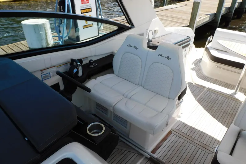 Not Guilty Yacht Photos Pics 2018 Sea Ray Sundancer 320 cockpit with white seating and helm, docked by the water.