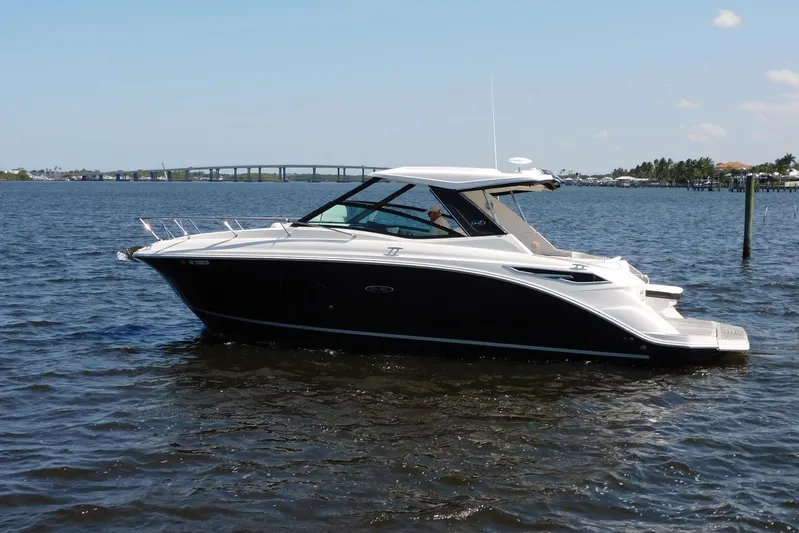 Not Guilty Yacht Photos Pics 2018 Sea Ray Sundancer 320 cruising on a sunny day, with a scenic bridge in the background.