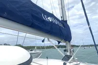 Sailboat with blue cover, Leopard 40 model, 2009, anchored in a scenic bay.